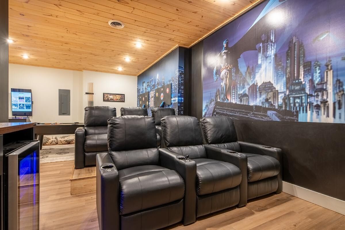 Ein Heimkino mit großer Leinwand, Ledersesseln und einer Holzbeschichtung an der Decke.