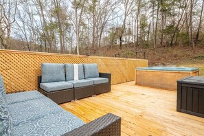Eine Holzterrasse mit einer Sitzecke und einem Whirlpool.