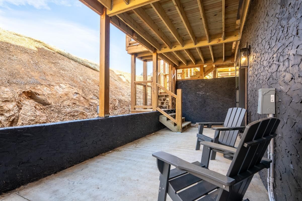 Un espace extérieur abrité, doté de fauteuils Adirondack, d’un escalier et d’un mur en pierre.
