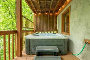 Ein Whirlpool auf einer Holzterrasse mit Blick auf Bäume.