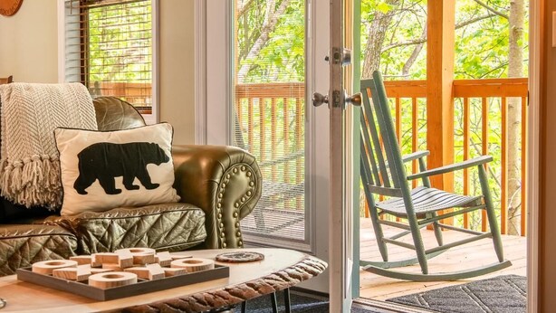 A cozy room with a leather couch, a wooden table with wooden blocks, and a rocking chair. - Bear Run Getaway (Gatlinburg)