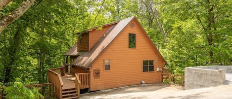 A cabin with a wooden exterior, a porch, and a small deck.