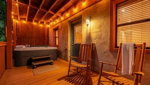 A wooden deck with a hot tub, two wooden chairs, and a bench. - Bear Run Getaway (Gatlinburg)