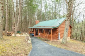 A log cabin with a porch, surrounded by trees. - Starwood (Sevierville)
