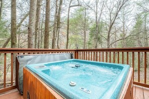 A hot tub on a wooden deck with a forest backdrop. - Starwood (Sevierville)