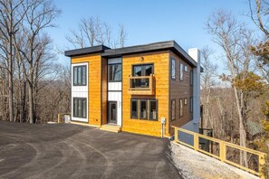 A modern two-story building with large windows, a balcony, and a wooden exterior. - Trinity (Sevierville)