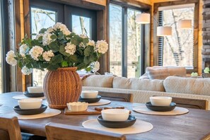 A dining table with white plates, black bowls, and a wicker vase with white flowers. - Trinity (Sevierville)