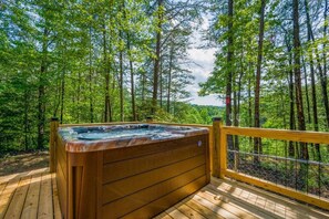 A hot tub on a wooden deck surrounded by a forest. - Call of the Wild (Sevierville)
