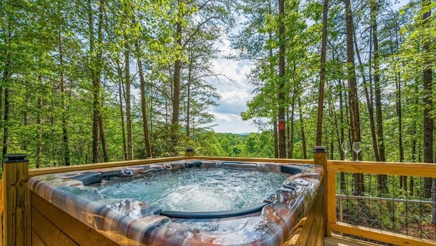 Ein Whirlpool, umgeben von einer Holzterrasse und einem Wald.