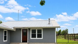 A single-story house with a metal roof, a front door, and a small front yard.