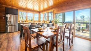 A wooden interior with a kitchen, dining area, and large windows. - Sunset Above the Smokies (Gatlinburg)