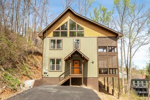 Eine zweistöckige Holzhütte mit Veranda, einer Treppe und einer Terrassenfläche.