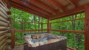 Una vasca idromassaggio in una baita di legno con vista sulla foresta.