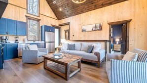 Interior de madera con cocina, sofá y sillas a rayas.