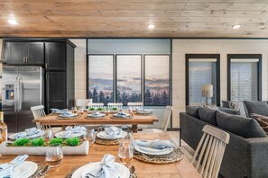 A dining area with a wooden table set for six, a sofa, and a kitchen with a refrigerator. - Timber & Stone (Sevierville)