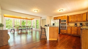 A spacious kitchen with wooden cabinets, a central island, and a dining area with natural light. - Family Mountain Lodge (Sevierville)