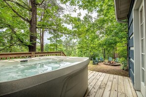 Ein Whirlpool auf einer Holzterrasse mit Blick auf ein bewaldetes Gebiet.