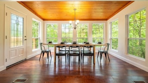 A dining area with a wooden ceiling, large windows, and a table set for four. - Family Mountain Lodge (Sevierville)