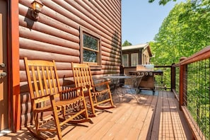 A log cabin with a deck, outdoor seating, and a grill. - Paradise Found (Sevierville)