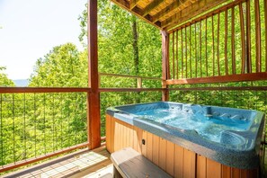 Ein Whirlpool auf einer Holzterrasse mit Blick auf einen Wald.