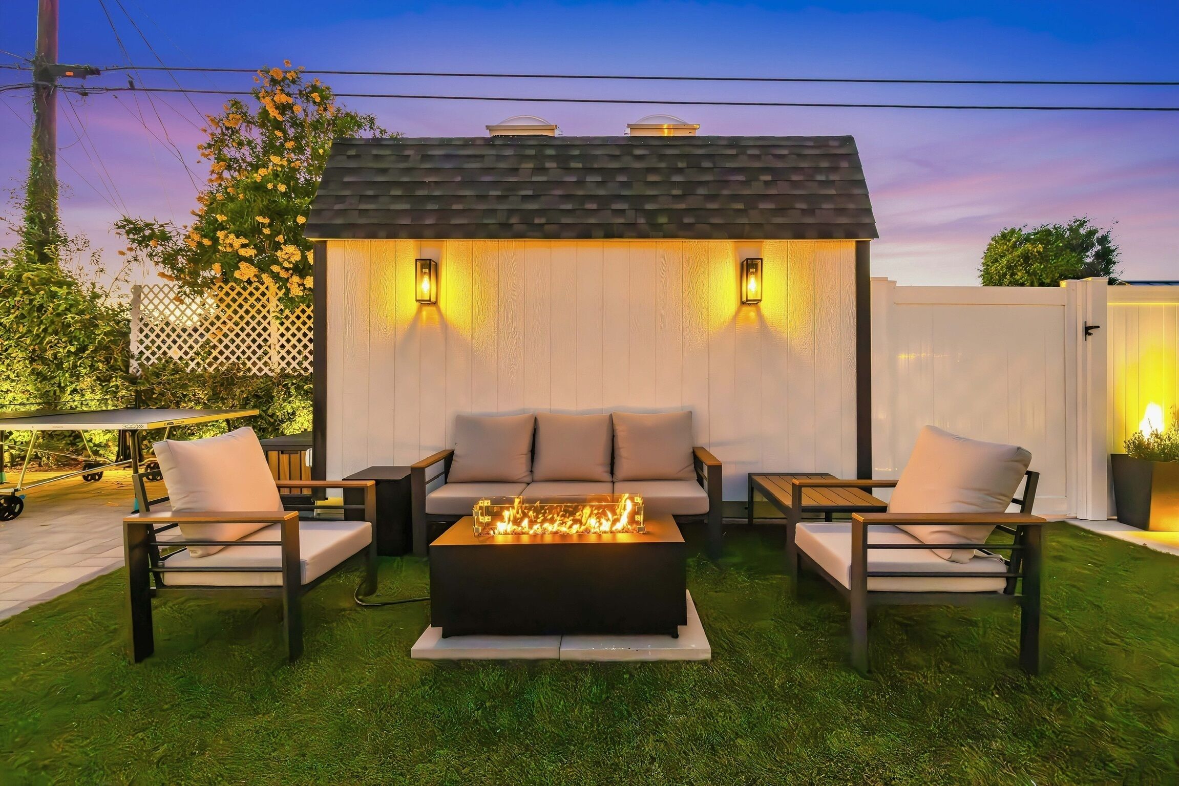 Eine Außenpatio mit Feuerstelle, zwei Sofas und einem Esstisch.