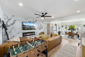 Ein modernes Wohnzimmer mit einem Kicker, einem Kamin und einem an der Wand befestigten Fernseher.