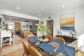Ein modernes Wohnzimmer mit Essbereich, einem Klavier und einem großen Gemälde an der Wand.