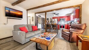 Una sala de estar con sofá, sillón reclinable, mesa de centro y televisor.