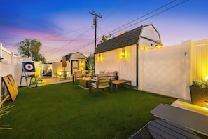 A backyard with artificial grass, a target, outdoor furniture, and a small shed. - Luxury 3BR Retreat | Hot Tub, Fire Pit & Games (Simi Valley)