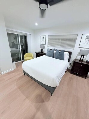 A modern bedroom with a large bed, a ceiling fan, and a sliding glass door leading to a balcony. - Luxury 3BR Retreat | Hot Tub, Fire Pit & Games (Simi Valley)