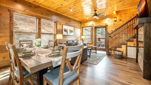 L’intérieur d’un chalet en bois comprend un coin repas, un escalier et une vue sur l’extérieur.