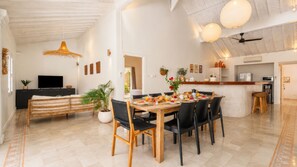A modern kitchen with a dining area, featuring a wooden table, chairs, and a TV. - Villa Mas Estate (Kuta)