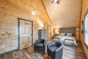 A log cabin bedroom with a bed, two chairs, a dresser, and a nightstand. - Z - Smoky Serenity Retreat (Sevierville)