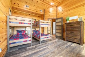 A cabin with bunk beds, wooden walls, and a dresser. - Fancy Views (Gatlinburg)