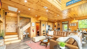 Un interior de madera con un sofá, una zona de comedor y una escalera.