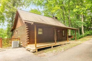 A log cabin with a porch, a chimney, and a window. - Lofty Pines (Sevierville)