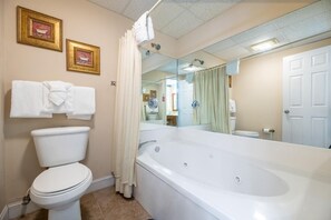 Ein Badezimmer mit Toilette, einer Badewanne, einem großen Spiegel und zwei gerahmten Bildern an der Wand.