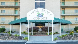 A building with a sign reading 'River Place Condos' and a covered entrance. - The Bears Den (Pigeon Forge)