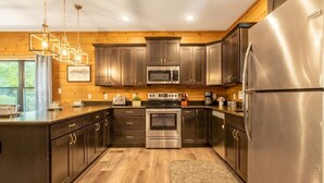 Une cuisine moderne avec des murs en bois, des appareils électroménagers en acier inoxydable et des luminaires suspendus.