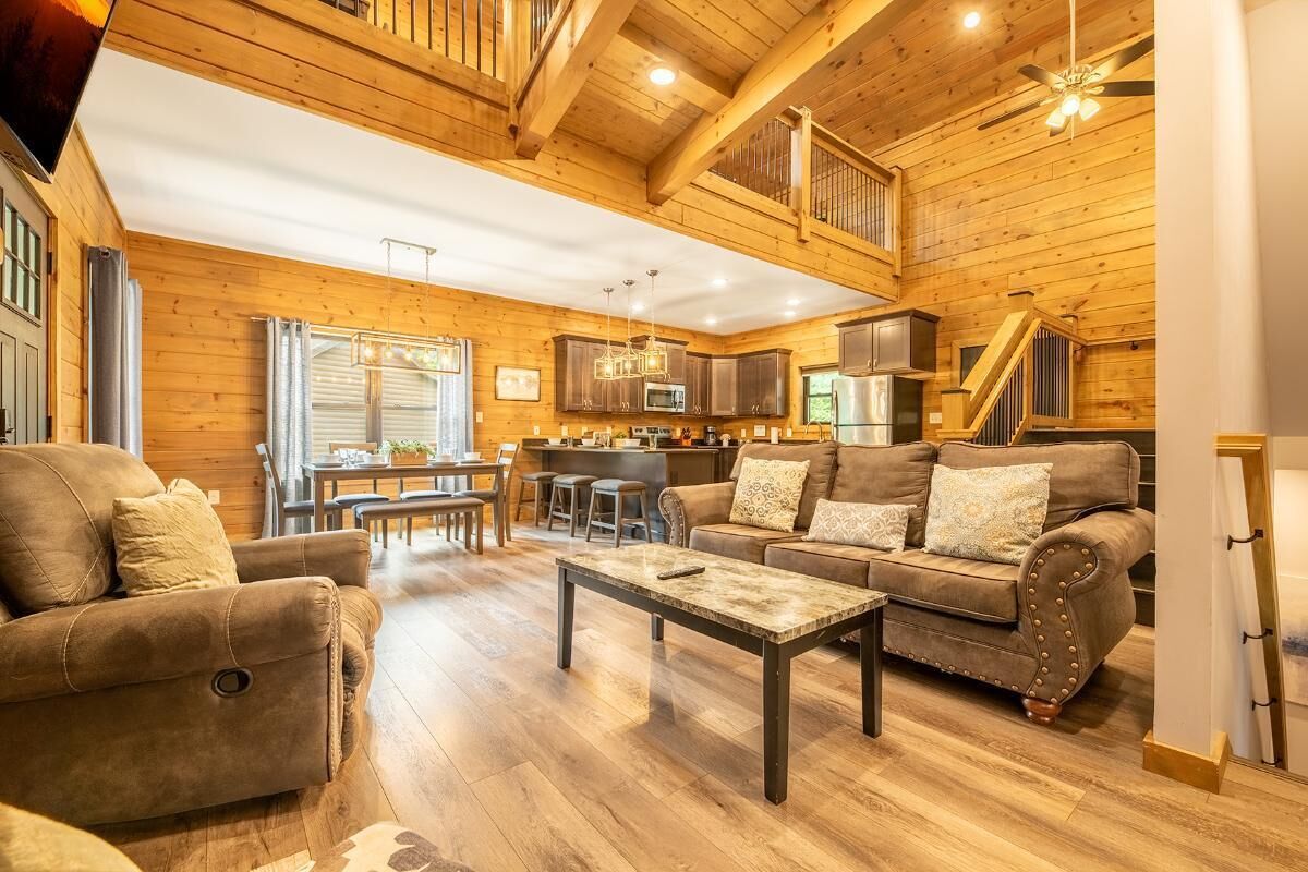 A spacious living room with a sofa, a coffee table, and a dining area with chairs and a table.