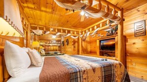 Een houten cabinemeubilair met een bed, een televisie en een plafondventilator.