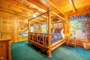 A log cabin interior with a four-poster bed, wooden walls, and a green carpet. - An Indian Dream (Sevierville)