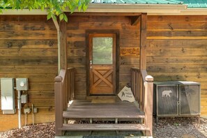 A wooden cabin entrance with a wooden door, a welcome sign, a metal kennel, and a sign reading 'Art Indian Dream.' - An Indian Dream (Sevierville)