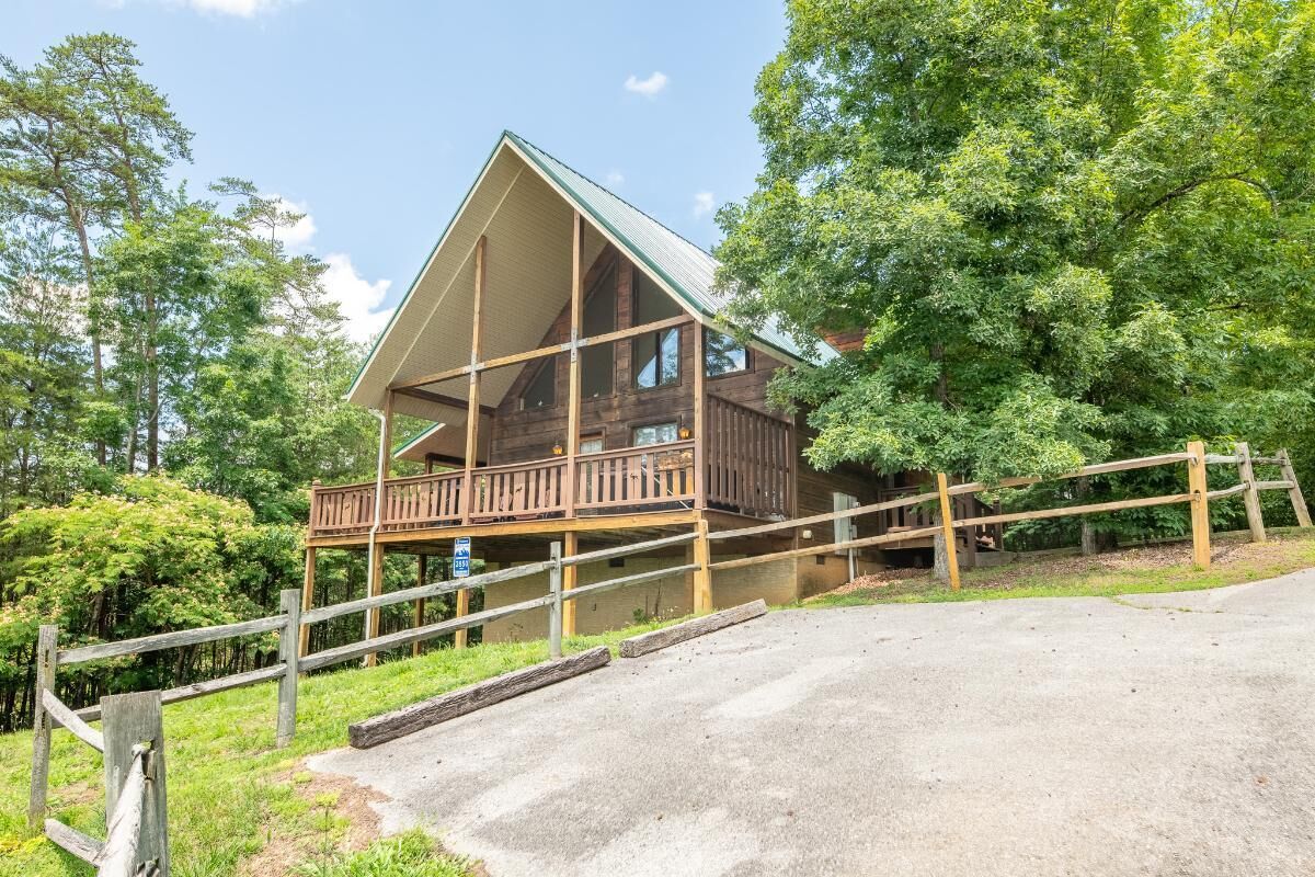 A wooden cabin with a balcony, surrounded by trees.