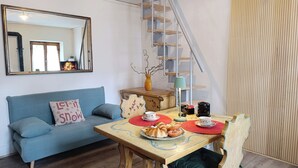 Ein gemütliches Wohnzimmer mit einem blauen Sofa, einem Holztisch mit Untertasse und einer Vase auf einer Kommode.