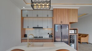Una cocina moderna con armarios grises, un refrigerador de acero inoxidable y una mesa de comedor de madera con sillas.