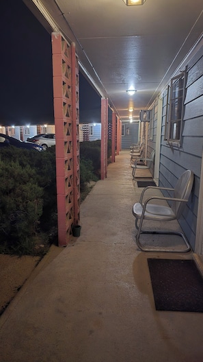 A covered outdoor area with chairs and a pathway leading to a building.