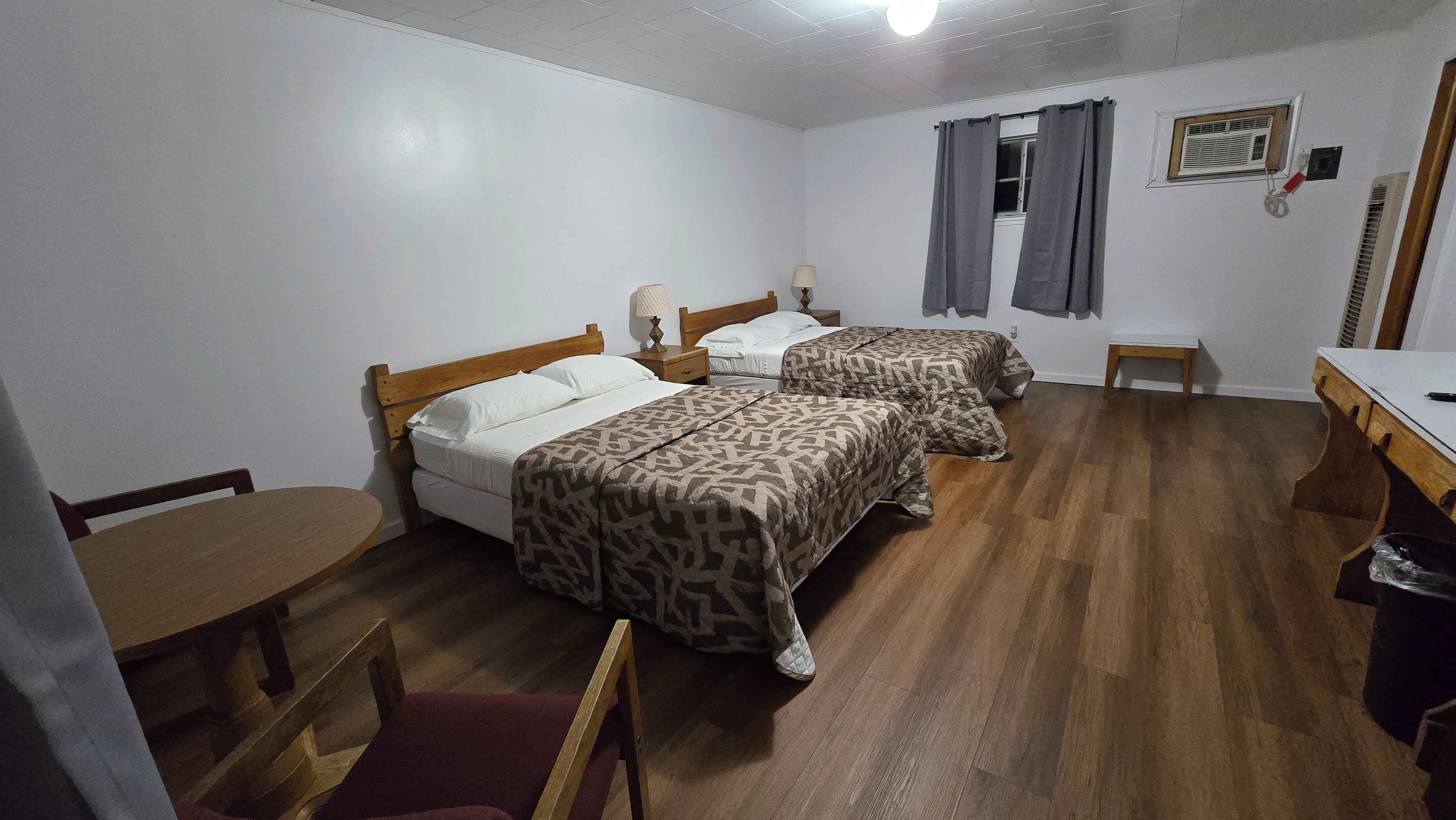Une chambre avec deux lits, un bureau, une chaise et une petite table.
