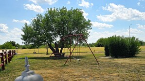 Un parque con un columpio, un farol y un árbol.
