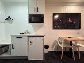 A compact kitchenette with a microwave, a small refrigerator, and a wooden table with chairs.